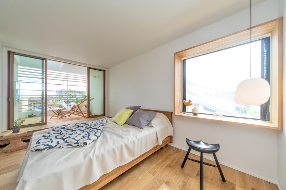 Diseño de dormitorio escandinavo con paredes blancas, suelo de madera en tonos medios y suelo marrón