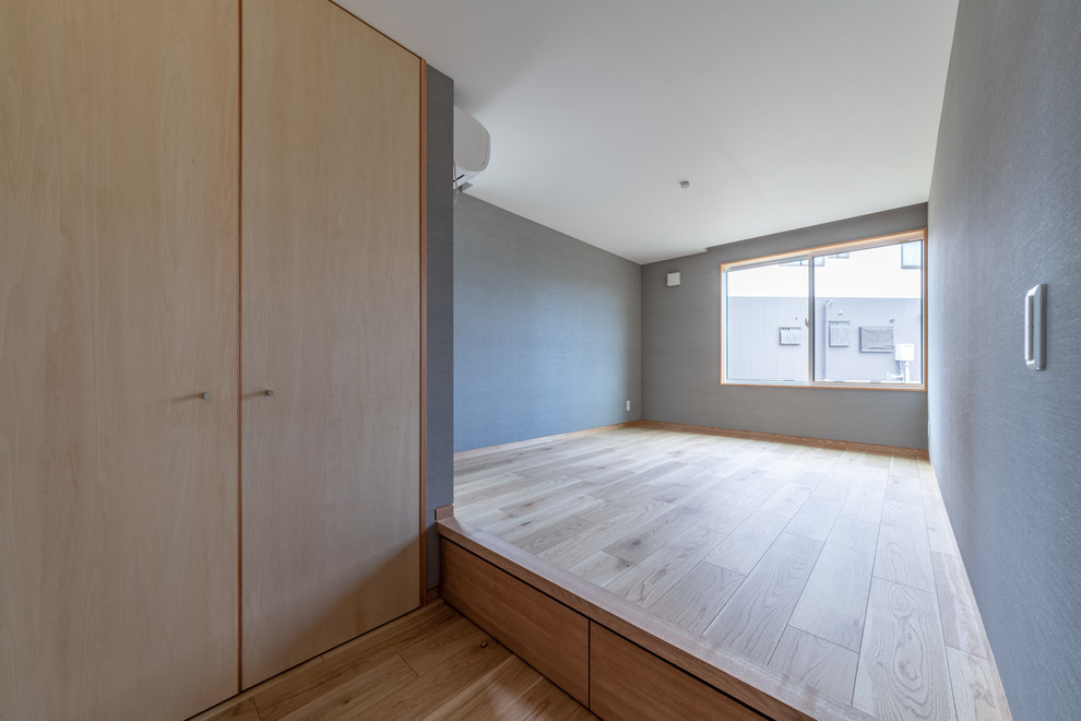 Diseño de dormitorio principal y blanco de estilo zen de tamaño medio con suelo de contrachapado, paredes grises, suelo marrón, papel pintado y papel pintado