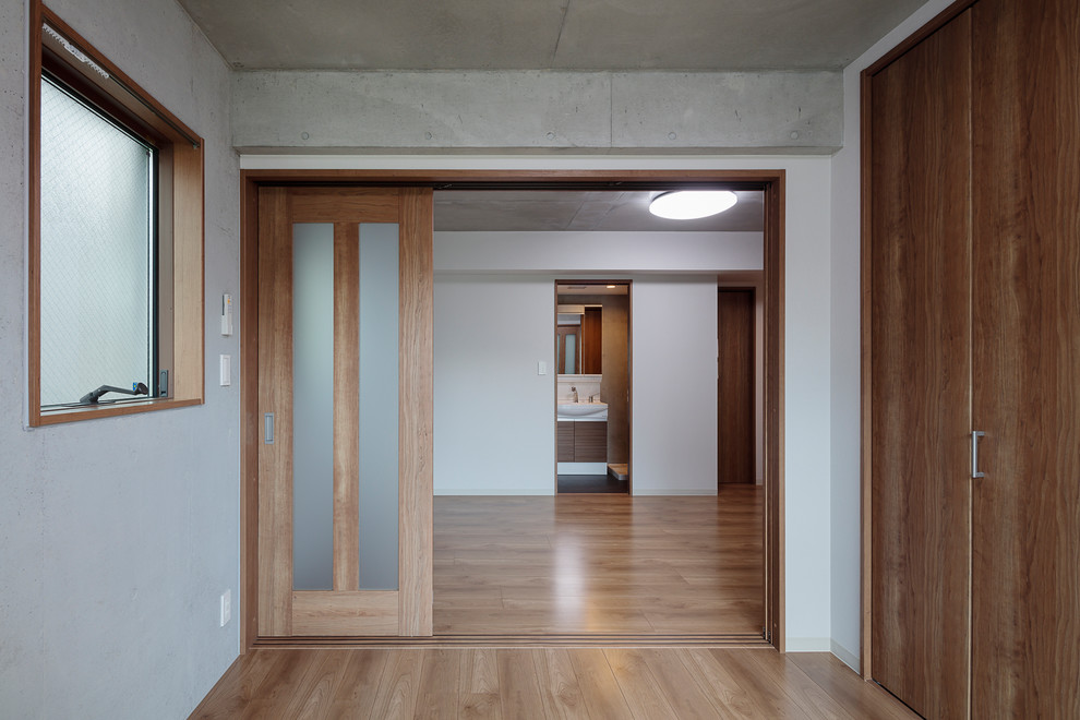 Modelo de dormitorio principal minimalista de tamaño medio con suelo de contrachapado, paredes multicolor y suelo marrón