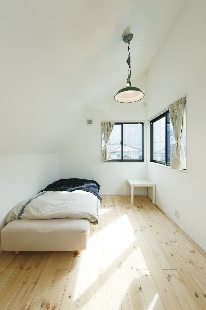 Inspiration pour une chambre mansardée ou avec mezzanine nordique avec un mur blanc, parquet clair et un sol blanc.