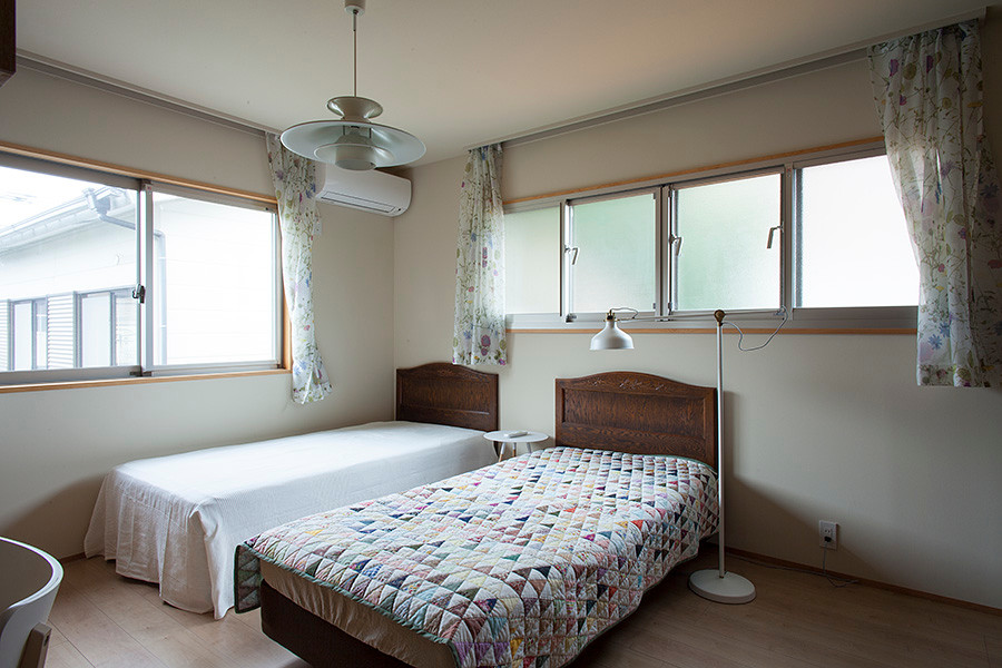 Mittelgroßes Landhaus Hauptschlafzimmer mit weißer Wandfarbe, Sperrholzboden, Hängekamin und beigem Boden in Sonstige