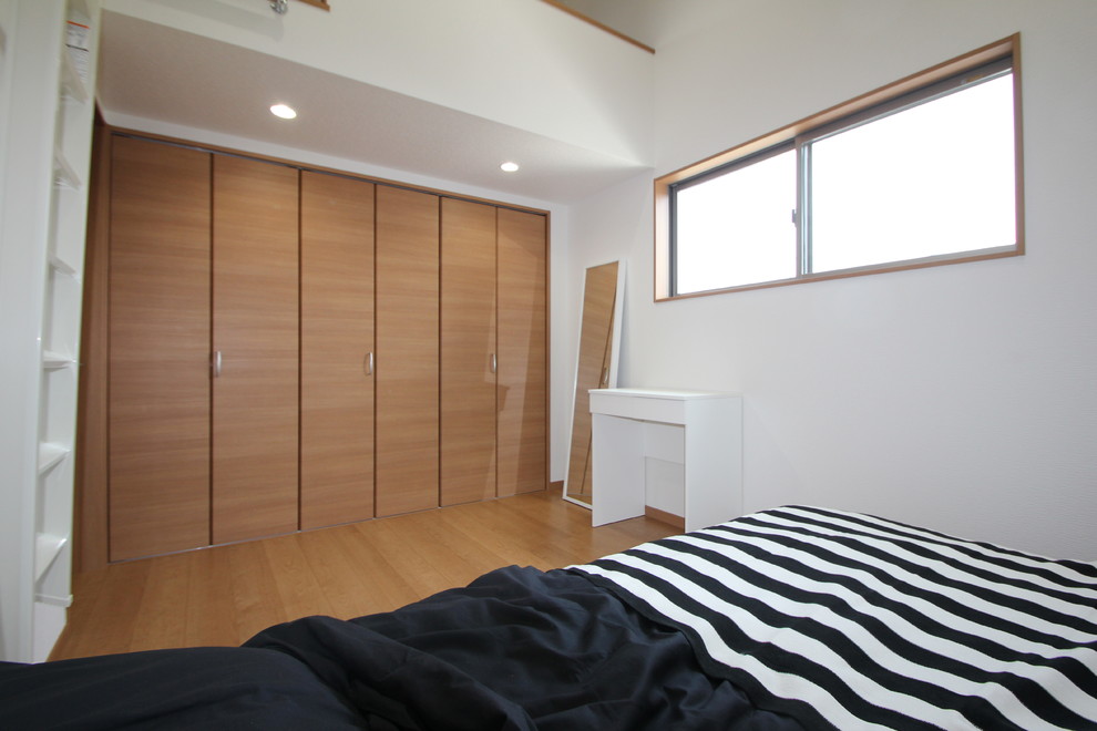 Modern inredning av ett sovloft, med vita väggar, plywoodgolv och beiget golv