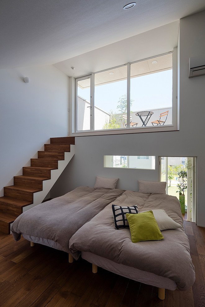 Пример оригинального дизайна: хозяйская спальня в стиле модернизм с белыми стенами, темным паркетным полом и коричневым полом без камина