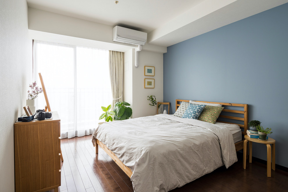 Großes Nordisches Hauptschlafzimmer mit blauer Wandfarbe und dunklem Holzboden in Tokio