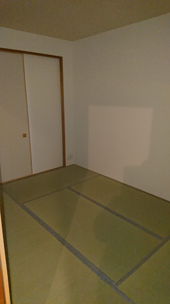 Cette image montre une petite chambre parentale traditionnelle avec un mur blanc et un sol de tatami.