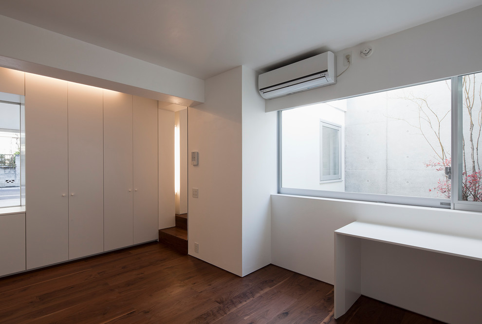 Photo of a modern master bedroom in Tokyo with white walls, dark hardwood flooring and brown floors.
