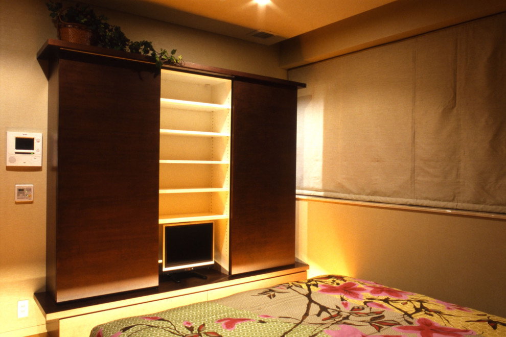 Foto di una camera matrimoniale etnica con pavimento in compensato, pavimento marrone e pareti beige