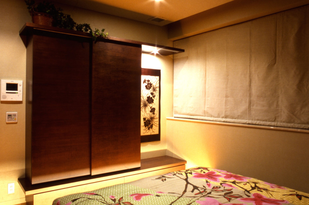 Esempio di una camera matrimoniale etnica con pavimento in compensato, pavimento marrone e pareti beige