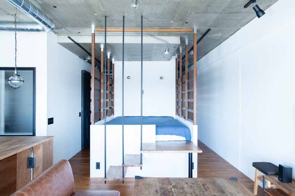 Ispirazione per una camera da letto industriale di medie dimensioni con pareti bianche, pavimento in legno massello medio e pavimento marrone