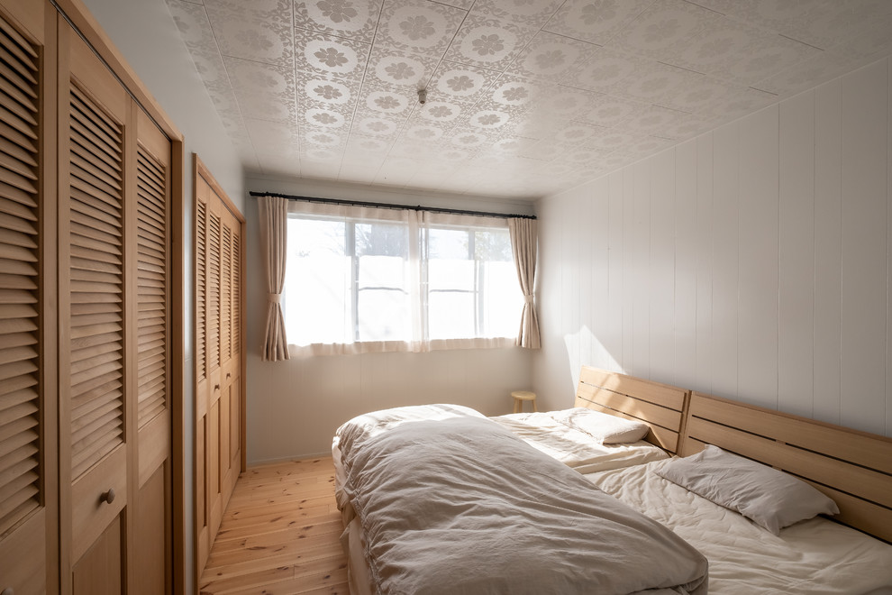 他の地域にあるカントリー風のおしゃれな寝室 (白い壁、無垢フローリング、茶色い床)