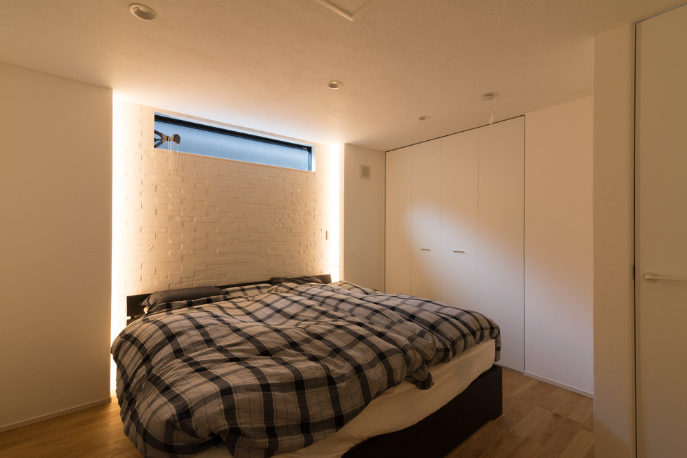 Eklektisches Hauptschlafzimmer mit weißer Wandfarbe, braunem Holzboden und beigem Boden in Tokio