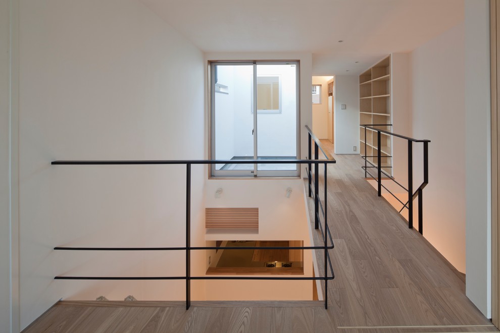 Esempio di una camera da letto stile loft minimalista di medie dimensioni con pareti bianche, nessun camino, pavimento marrone e pavimento in compensato