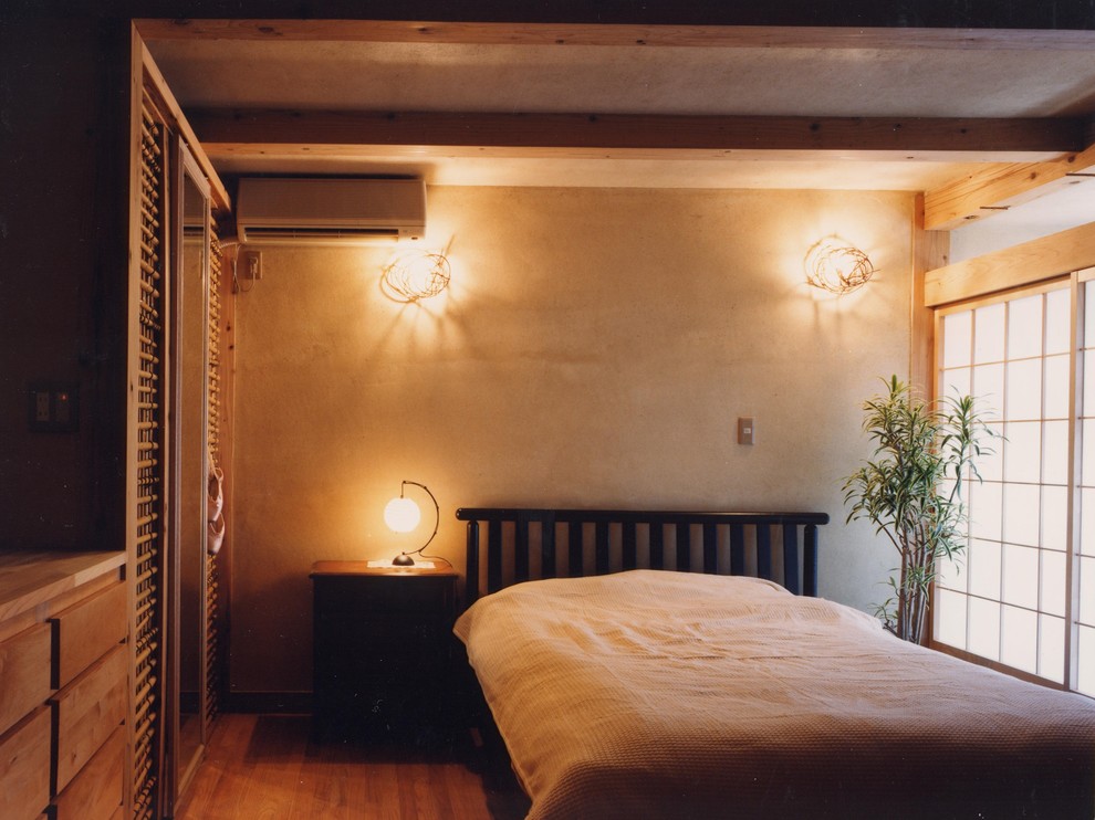 Foto di una camera matrimoniale etnica con pareti beige, pavimento in legno massello medio, nessun camino e pavimento marrone