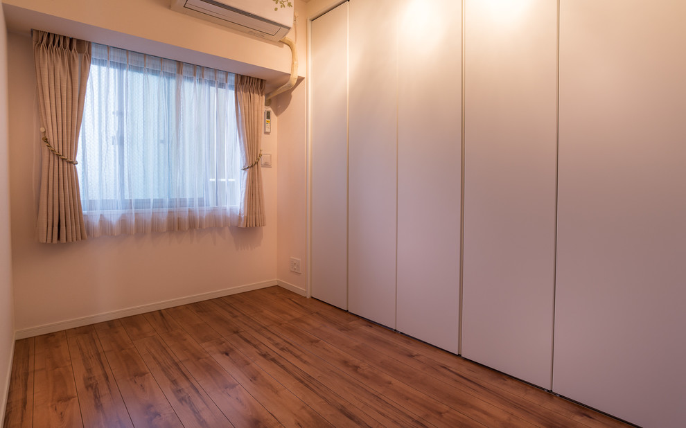 Modelo de habitación de invitados nórdica grande sin chimenea con paredes blancas, suelo de contrachapado y suelo marrón