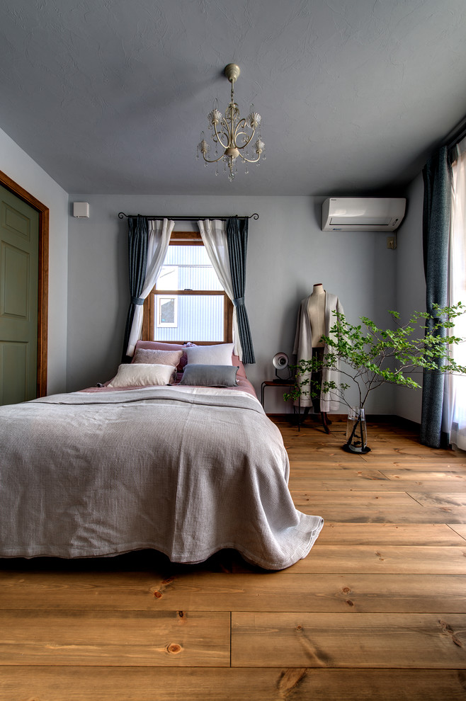 Modelo de dormitorio gris retro con paredes grises, suelo de madera en tonos medios y suelo marrón