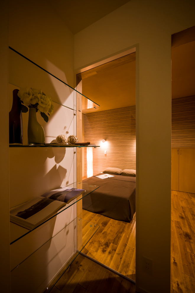 Ispirazione per una camera matrimoniale minimalista con pareti beige, pavimento in legno massello medio e pavimento marrone