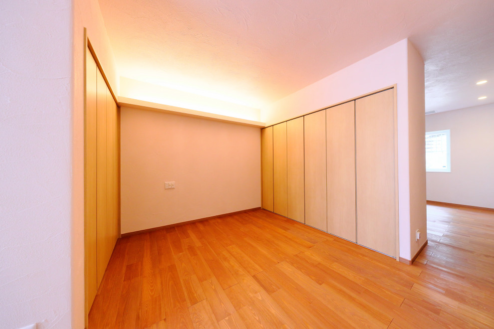 Mittelgroßes Asiatisches Hauptschlafzimmer mit weißer Wandfarbe und braunem Holzboden in Nagoya