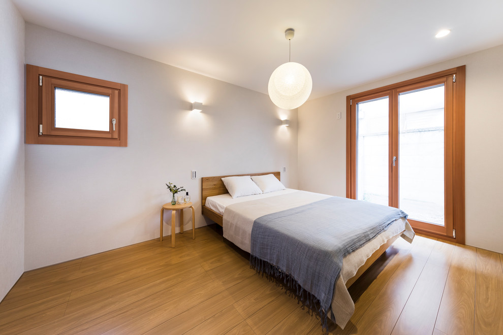 Cette photo montre une petite chambre parentale moderne avec un mur blanc, un sol en bois brun, aucune cheminée et un sol marron.
