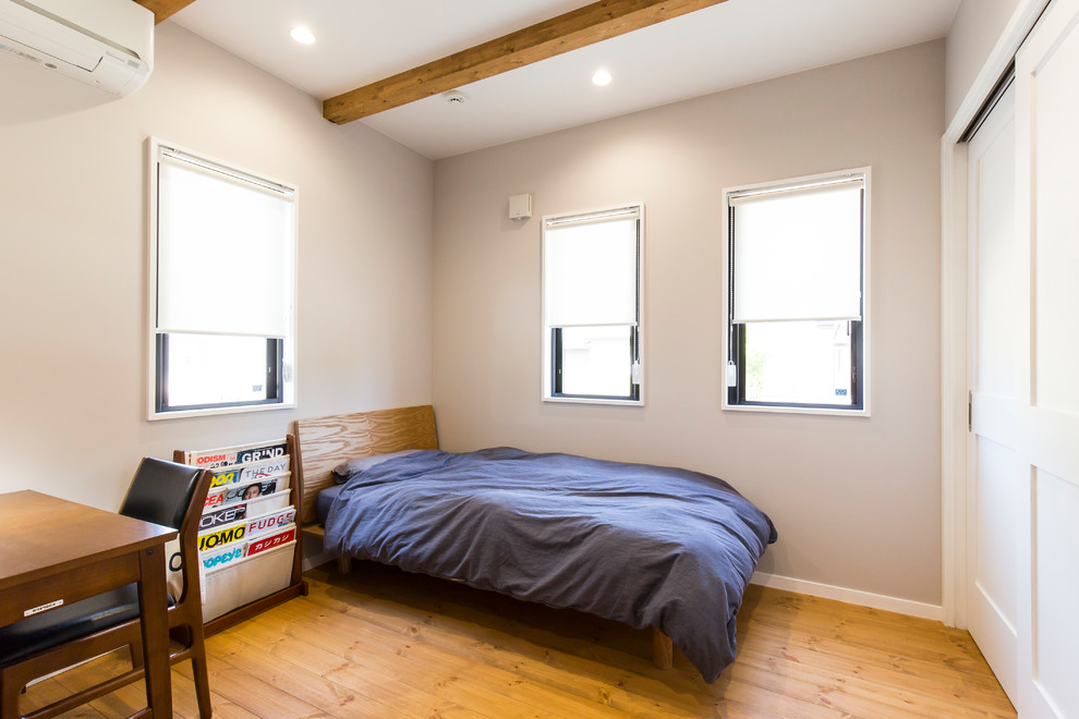 Immagine di una camera da letto industriale con pareti grigie, pavimento in legno massello medio e pavimento grigio