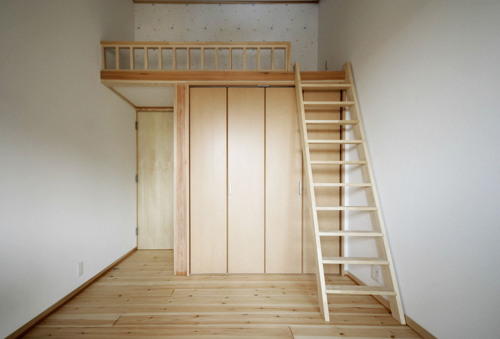 Diseño de dormitorio tipo loft asiático grande sin chimenea con paredes blancas, suelo de madera clara y suelo beige