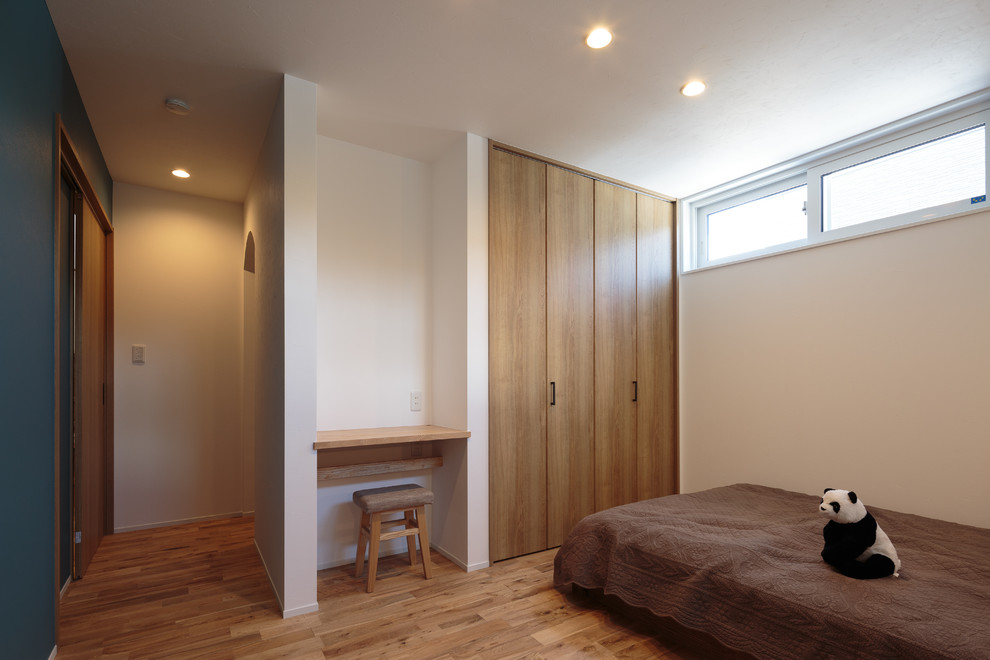 Idée de décoration pour une chambre parentale nordique avec un mur bleu, un sol en bois brun et un sol beige.