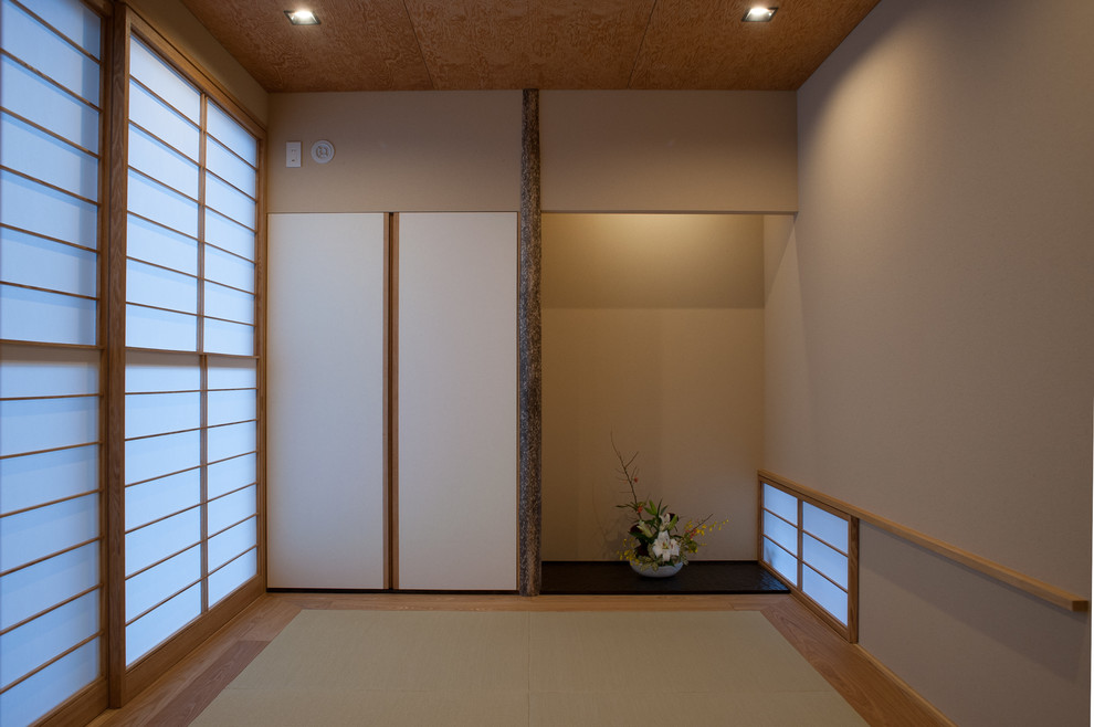 Cette image montre une chambre d'amis asiatique avec un mur beige, un sol de tatami et aucune cheminée.