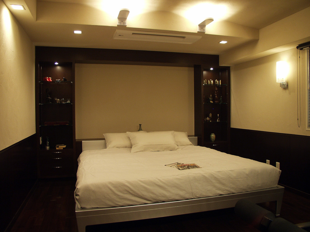 Réalisation d'une grande chambre parentale minimaliste avec un mur beige et un sol en bois brun.