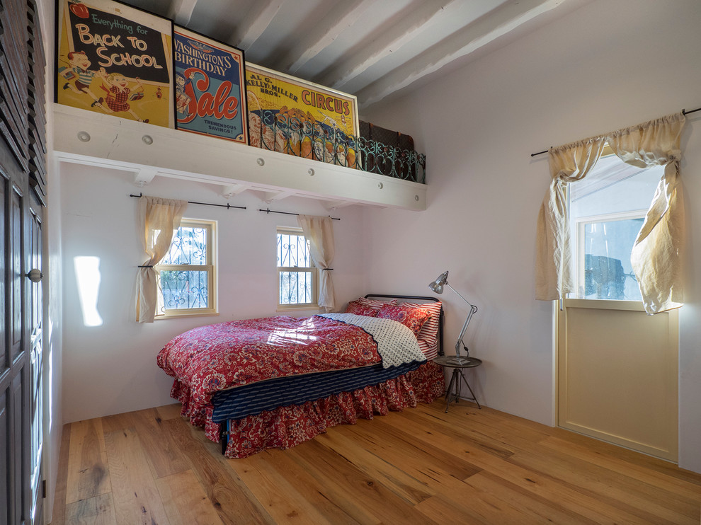 Diseño de dormitorio principal mediterráneo pequeño sin chimenea con paredes blancas y suelo de madera en tonos medios