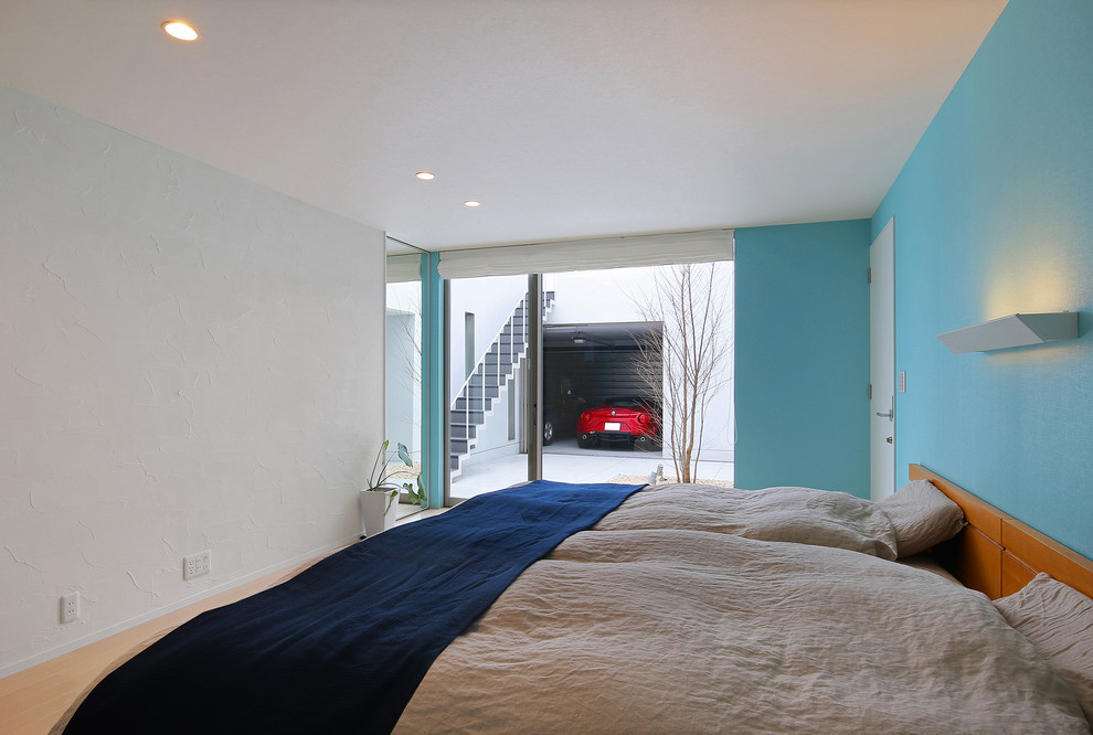 Ejemplo de dormitorio actual con paredes azules, suelo de madera clara y suelo marrón