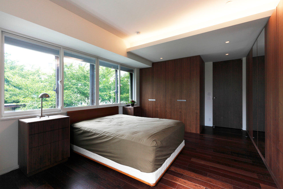 Esempio di una camera matrimoniale minimalista con parquet scuro, pareti bianche e pavimento marrone