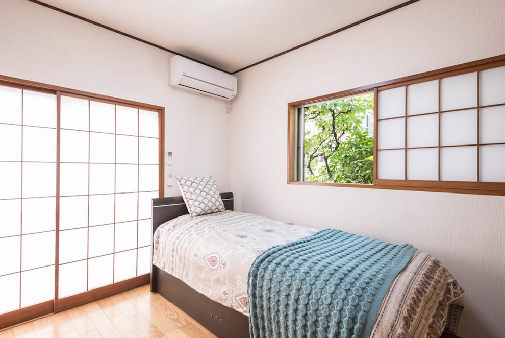 Modelo de dormitorio principal asiático con paredes blancas, suelo de contrachapado y suelo beige