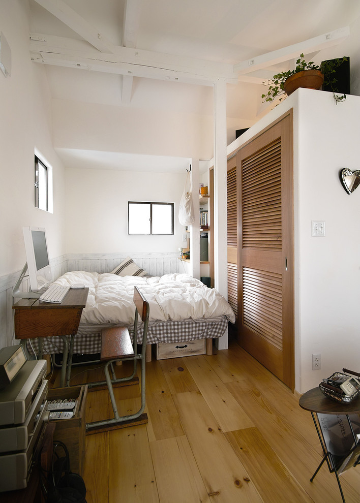 Diseño de dormitorio campestre pequeño con paredes blancas, suelo de madera en tonos medios y suelo marrón