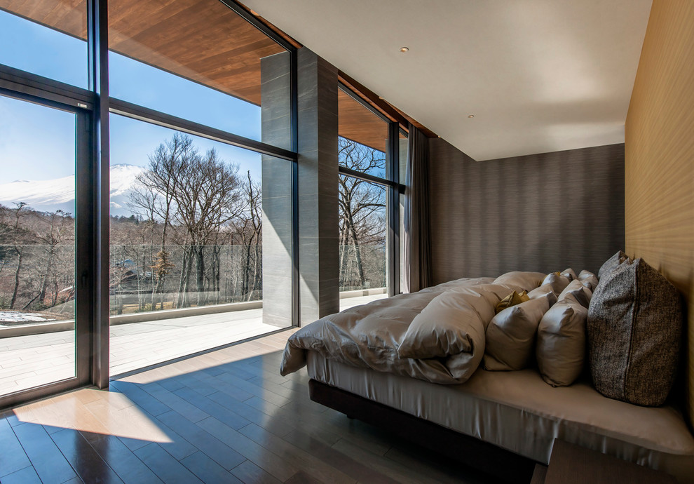 Стильный дизайн: хозяйская спальня в современном стиле с разноцветными стенами, деревянным полом и коричневым полом без камина - последний тренд