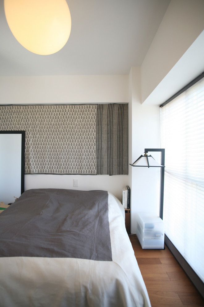 Idée de décoration pour une petite chambre parentale minimaliste avec un mur blanc, parquet foncé et un sol marron.