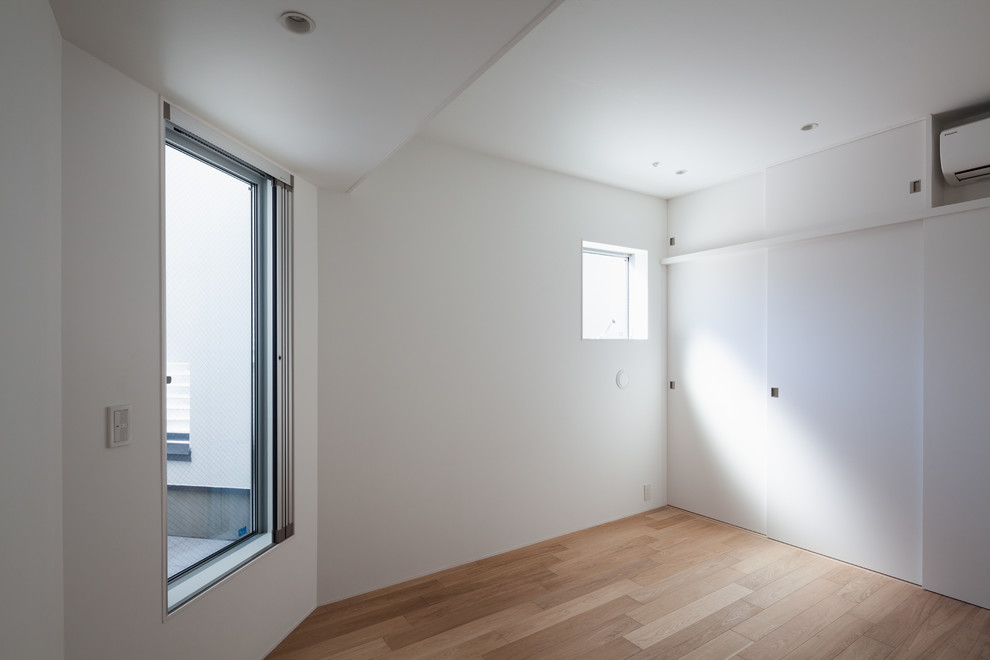 Kleines Modernes Hauptschlafzimmer ohne Kamin mit weißer Wandfarbe, Sperrholzboden und braunem Boden in Tokio