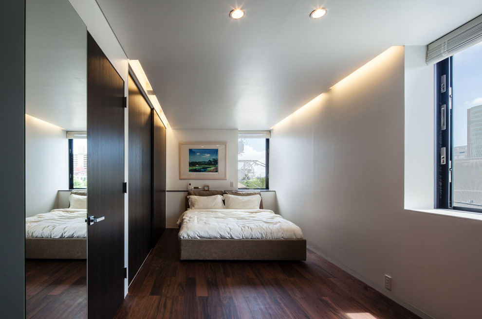 Imagen de dormitorio contemporáneo con paredes blancas, suelo de madera oscura y suelo marrón