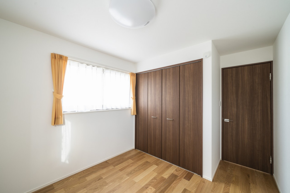 Modelo de dormitorio actual de tamaño medio con suelo de madera clara, suelo beige y papel pintado