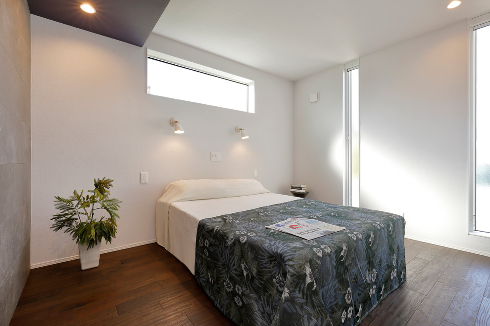 Hauptschlafzimmer mit weißer Wandfarbe, dunklem Holzboden und braunem Boden in Sonstige