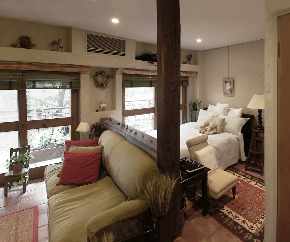 На фото: спальня в стиле кантри с белыми стенами, полом из терракотовой плитки и оранжевым полом с
