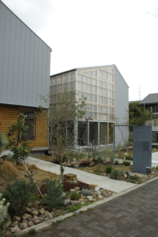 This is an example of a medium sized modern front partial sun garden in Kyoto with lawn edging and concrete paving.