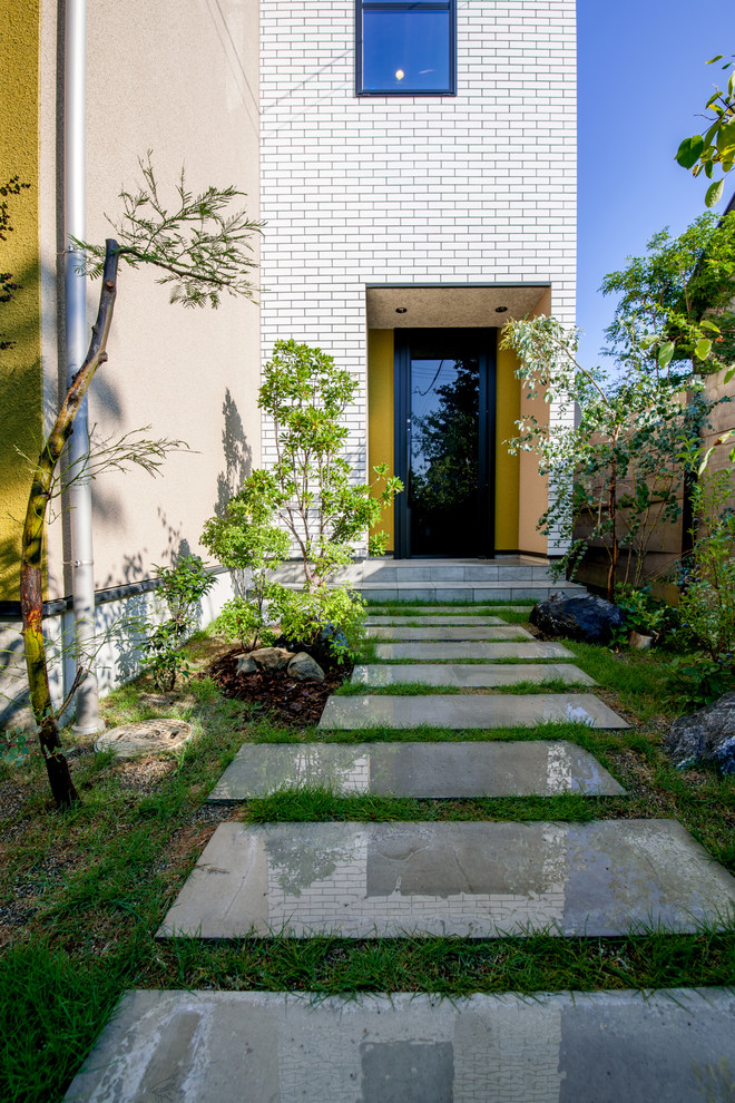 На фото: участок и сад на переднем дворе в стиле модернизм с полуденной тенью с