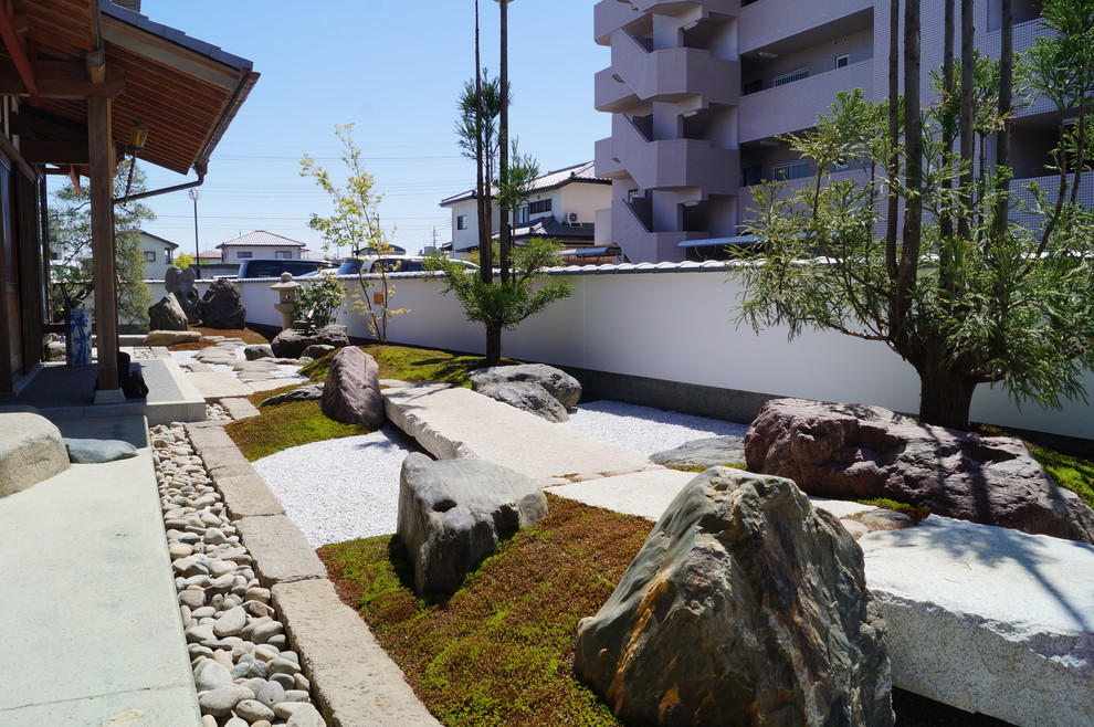 Cette image montre un jardin japonais avant asiatique avec une exposition ensoleillée et des pavés en pierre naturelle.