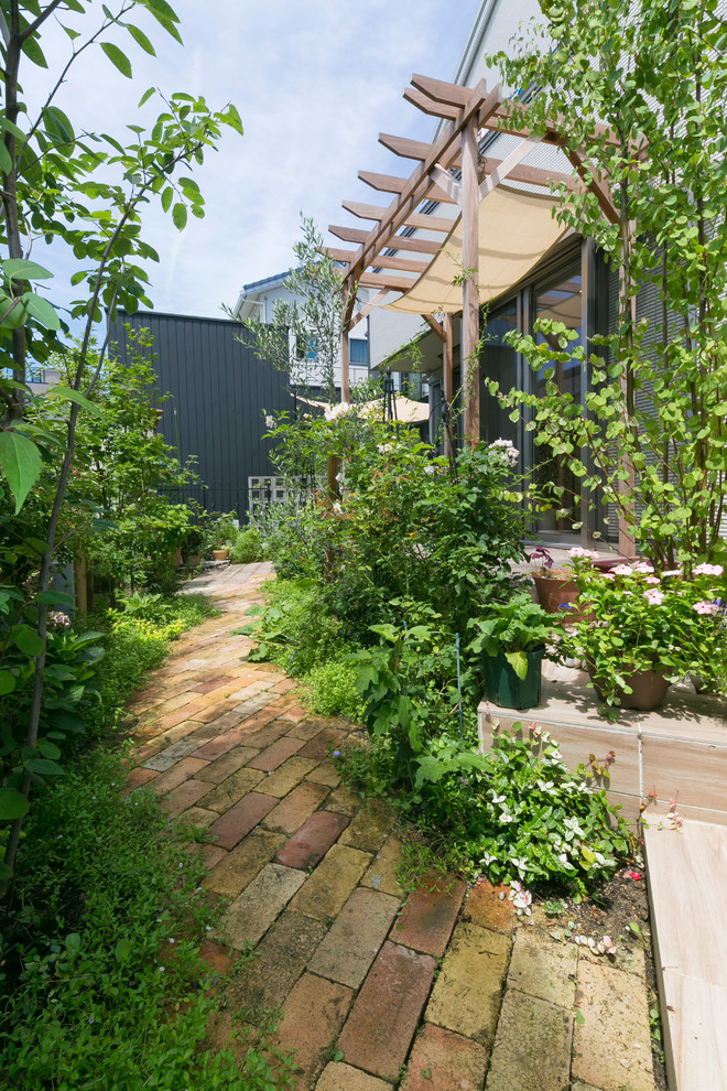 Aménagement d'un jardin arrière classique avec des pavés en brique et une exposition ensoleillée.