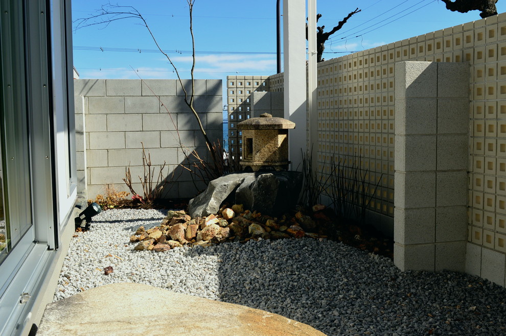 Diseño de jardín de secano moderno en invierno en patio trasero con roca decorativa, exposición parcial al sol y gravilla