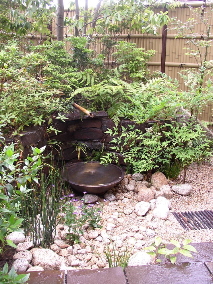 На фото: регулярный сад на заднем дворе в восточном стиле с покрытием из гравия