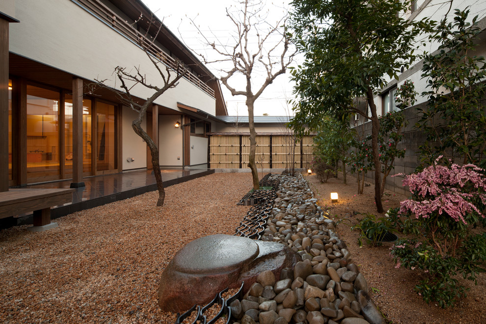 Réalisation d'un jardin japonais latéral asiatique avec du gravier.