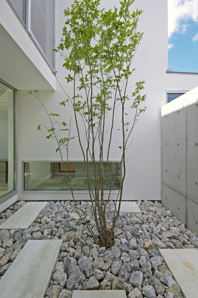 Imagen de jardín moderno en patio con roca decorativa, exposición reducida al sol y adoquines de piedra natural
