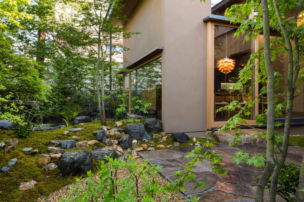 Inspiration för asiatiska formella trädgårdar längs med huset, med naturstensplattor