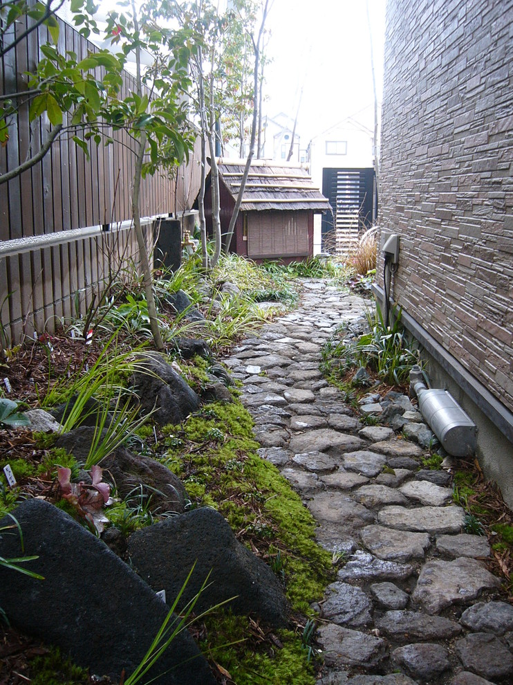 На фото: тенистый японский сад на боковом дворе в восточном стиле с покрытием из каменной брусчатки с