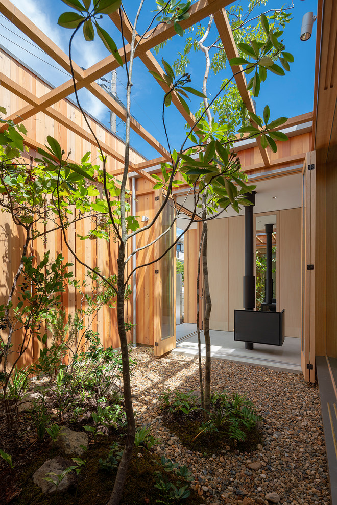 This is an example of a small world-inspired courtyard full sun garden for summer in Osaka with a fireplace, gravel and an outdoor sport court.